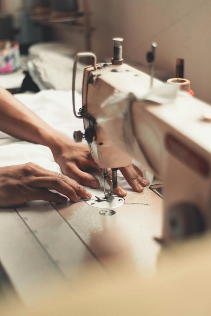 Close-up of hands using a sewing machine, highlighting the garment production process.