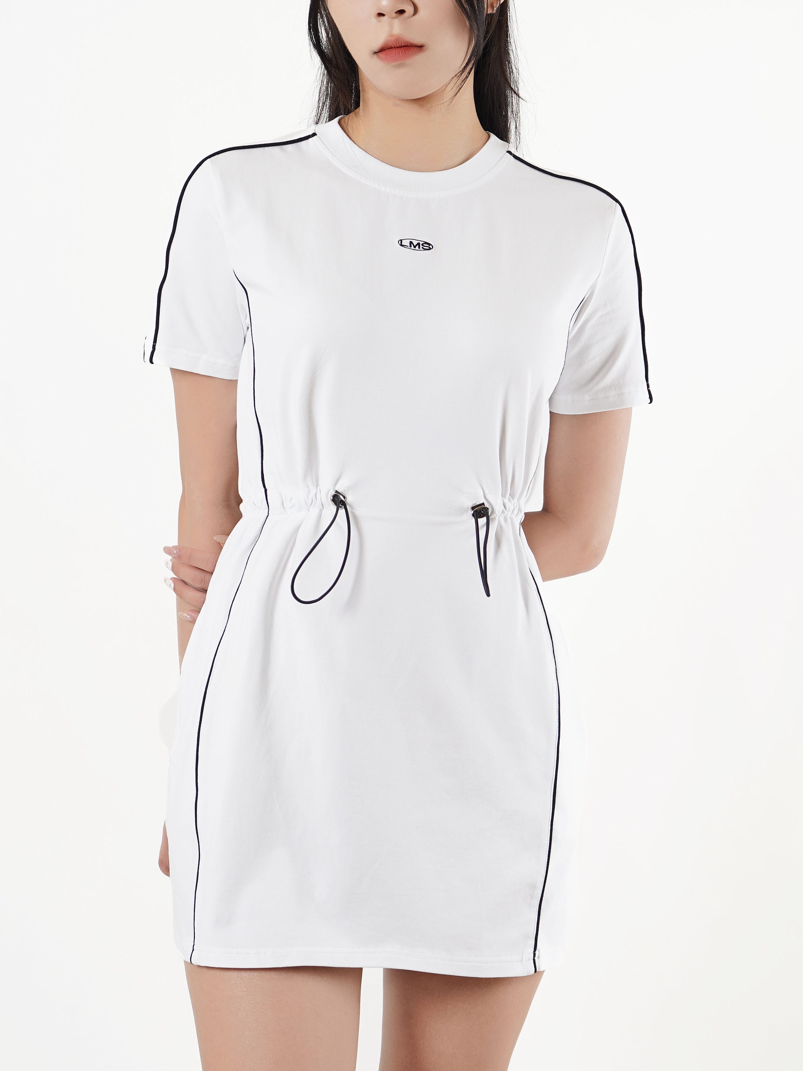 A model wearing a white short-sleeved dress with black piping and a drawstring waist, posing against a plain white background.