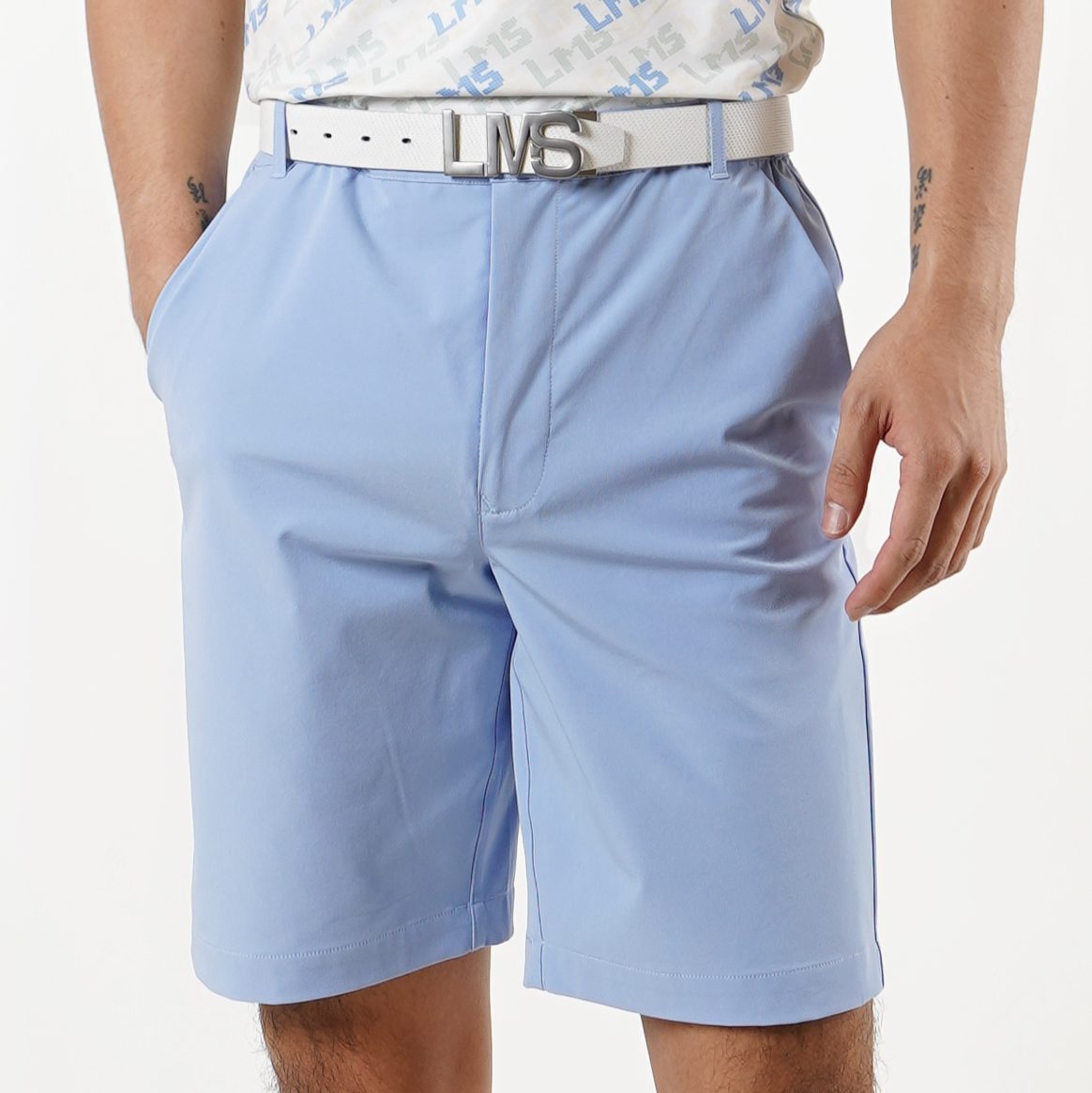 Close-up of a person wearing light blue shorts and a white belt with a metallic buckle, showcasing a casual fashion style.