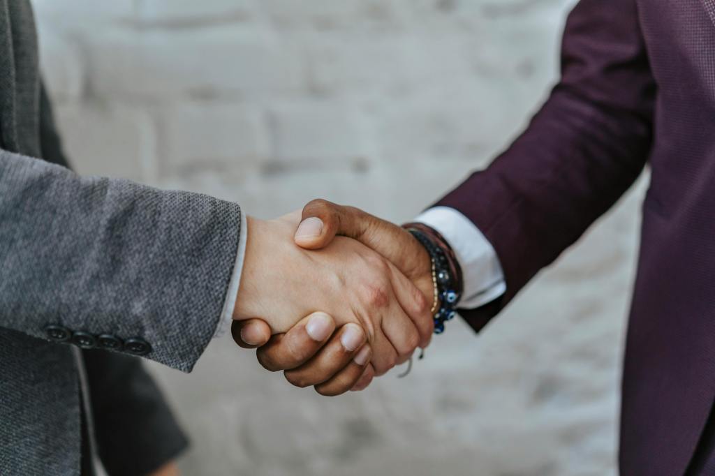 Close-up of two people shaking hands, representing partnership and collaboration.