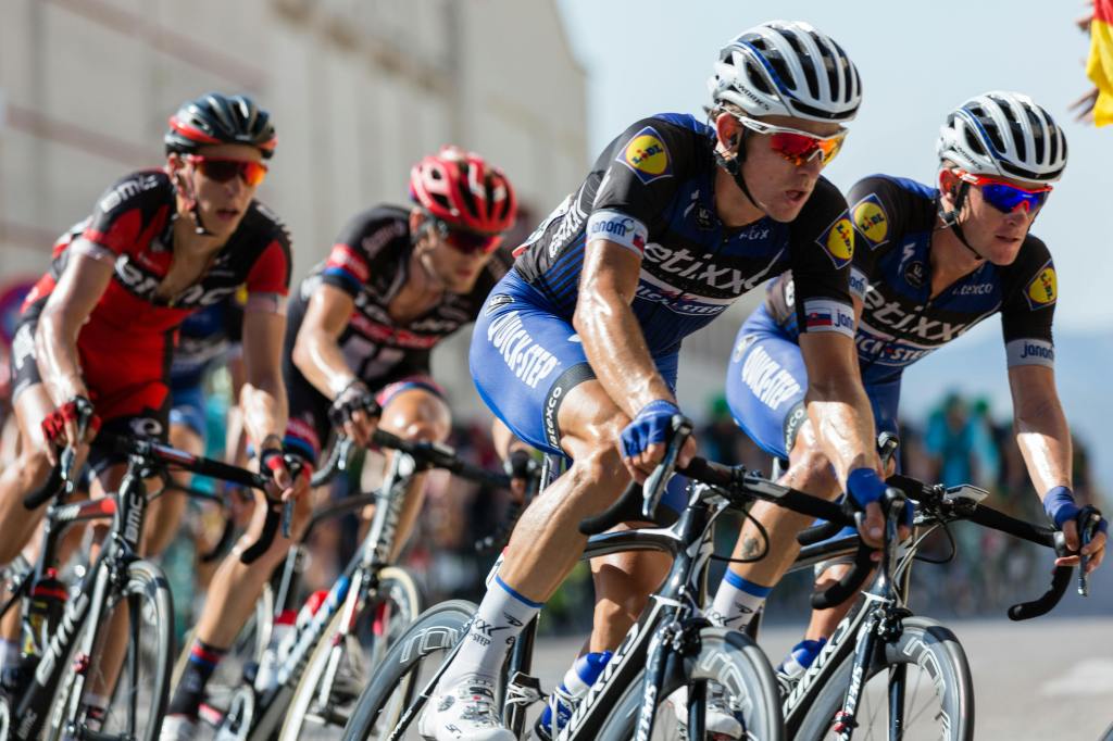 A group of competitive cyclists racing on a road, showcasing dynamic movement and athletic performance.
